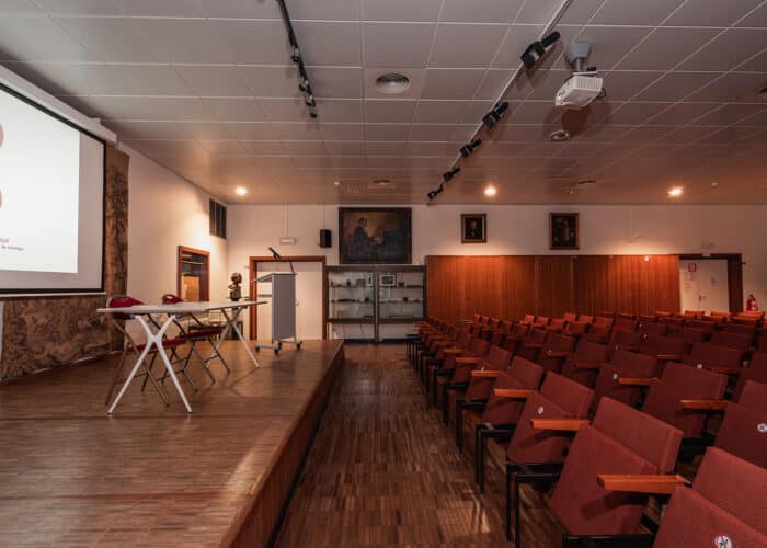 Salle Concert avec estrade, table, chaises, écran et sièges