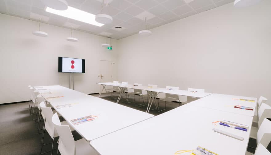 Salle de réunion studio avec tables, chaises et écran