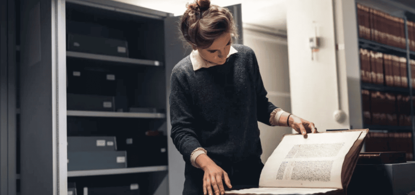 Femme lisant un manuscrit précieux conservé à KBR après l'avoir sorti d'une boîte